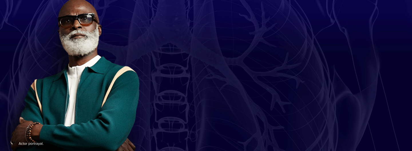 a male patient with a bread and glasses standing with his arms crossed against a blue background, overlaid with a translucent image of human lungs, symbolizing lung health.