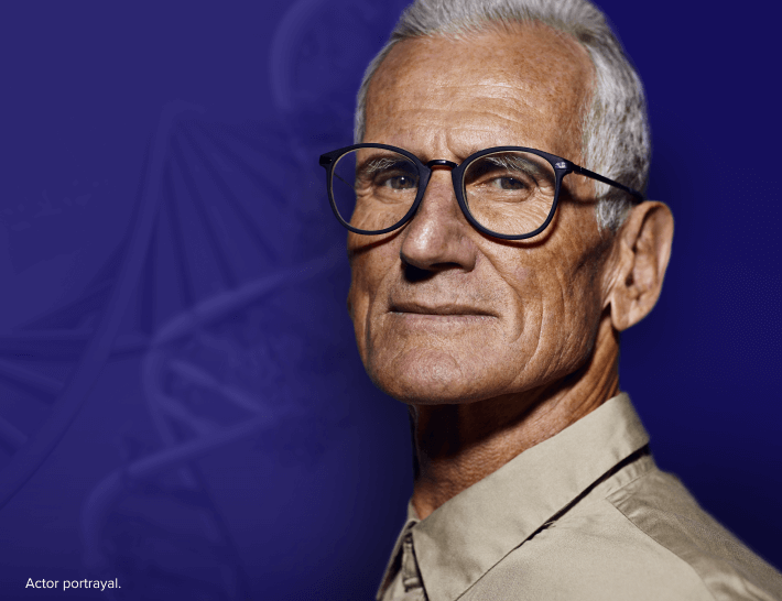 A man with glasses against a blue background, overlaid with a translucent image of a DNA strain.